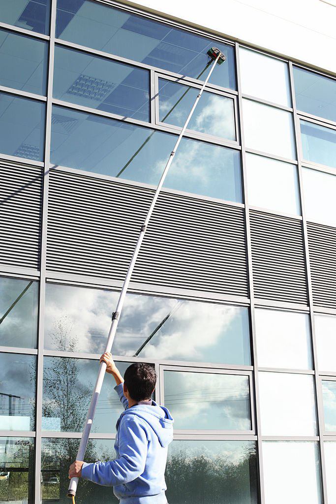 Window cleaner using a water-fed pole to reach upper floor windows